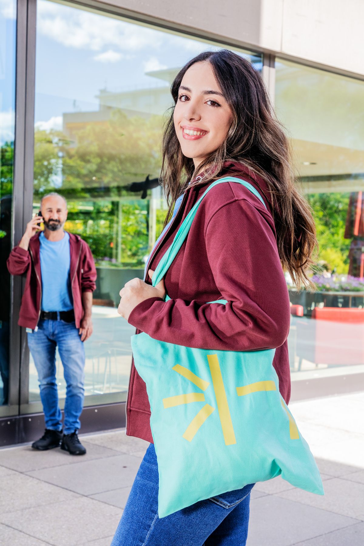 Employee with wine-red hoodie and turquoise tote bag USB merchandise