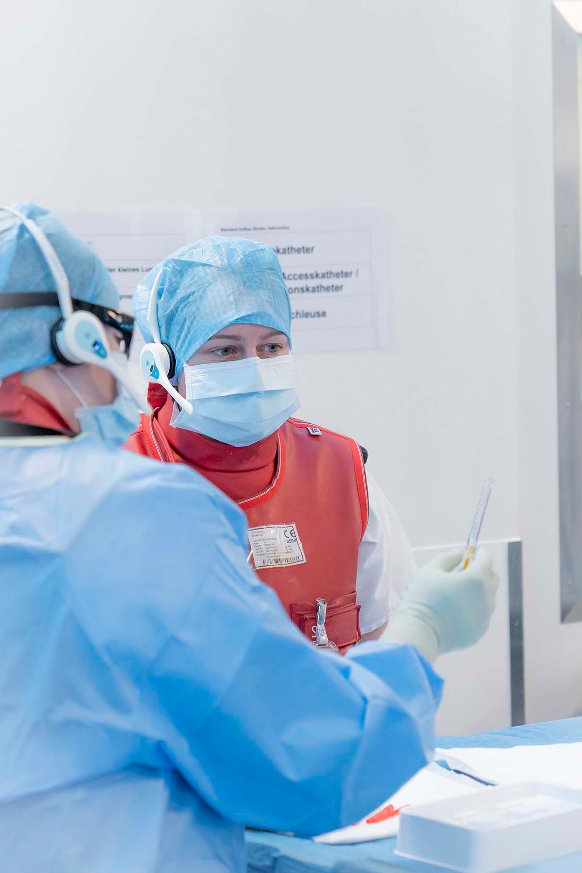 Zwei Radiologiefachpersonen bereiten bei einer komplexen neuroradiologischen Intervention das Medikament für die Embolisation vor