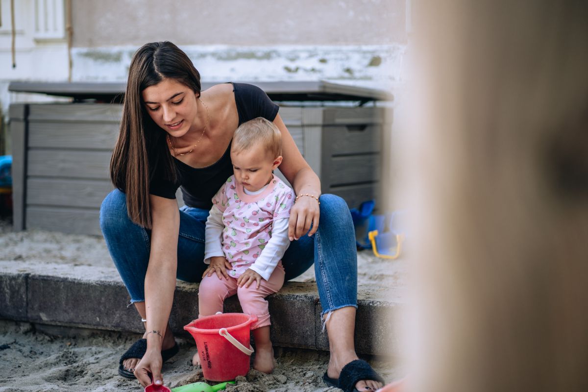 L'assistante maternelle joue avec un enfant sur l'aire de jeux