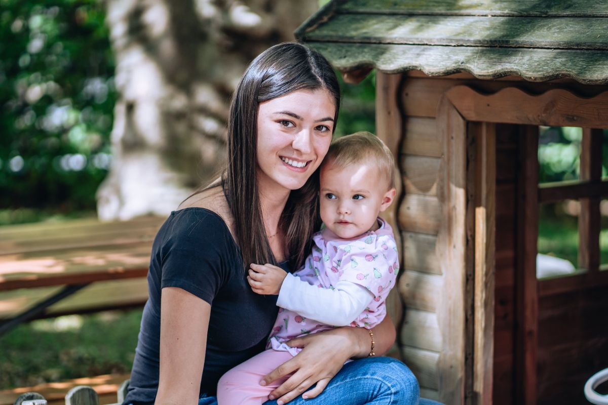 Assistante de vie assise sur un banc avec un petit enfant