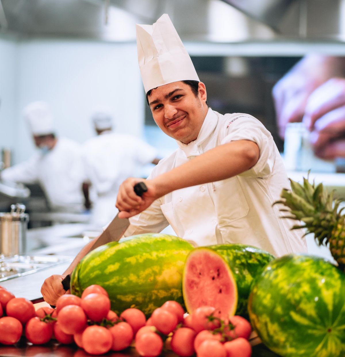 Trainee chef cuts a large watermelon with a knife